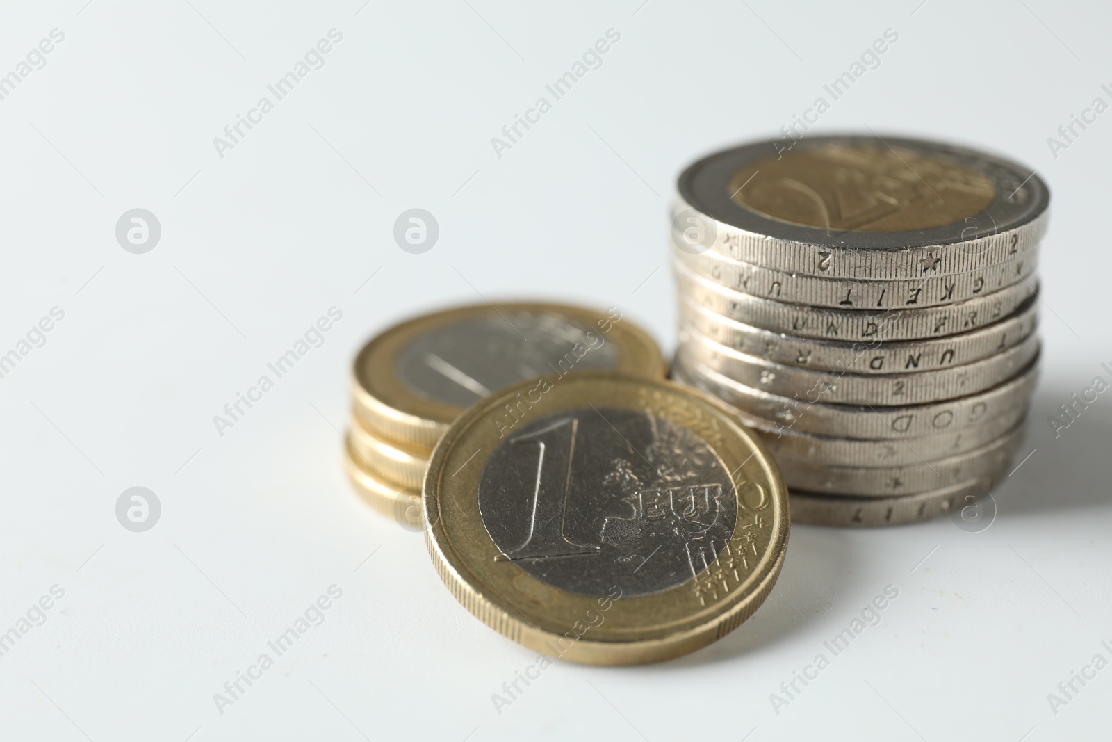 Photo of Stacked euro coins on white background, closeup