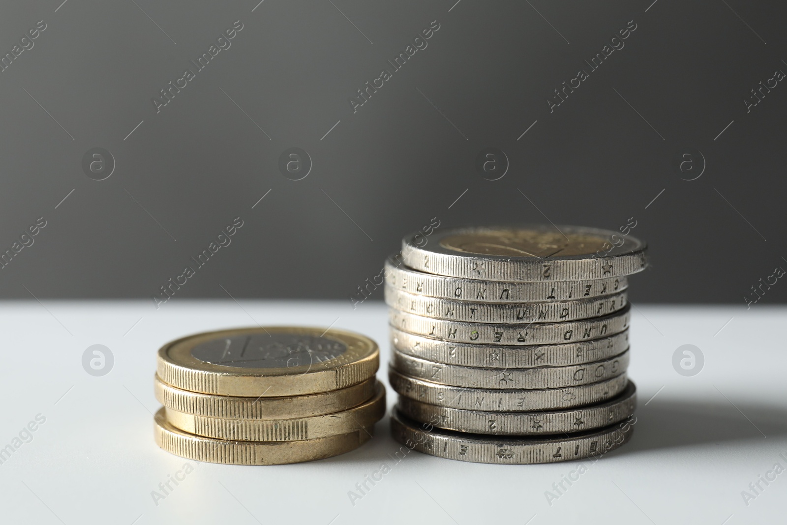 Photo of Stacked euro coins on white table, closeup