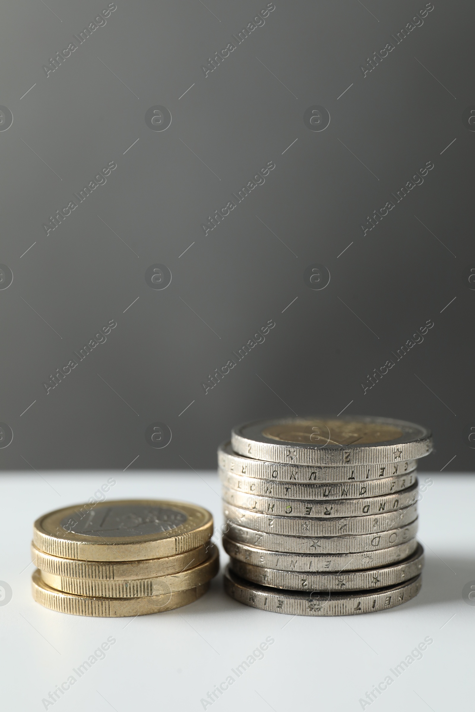 Photo of Stacked euro coins on white table, space for text