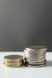 Photo of Stacked euro coins on white table, space for text