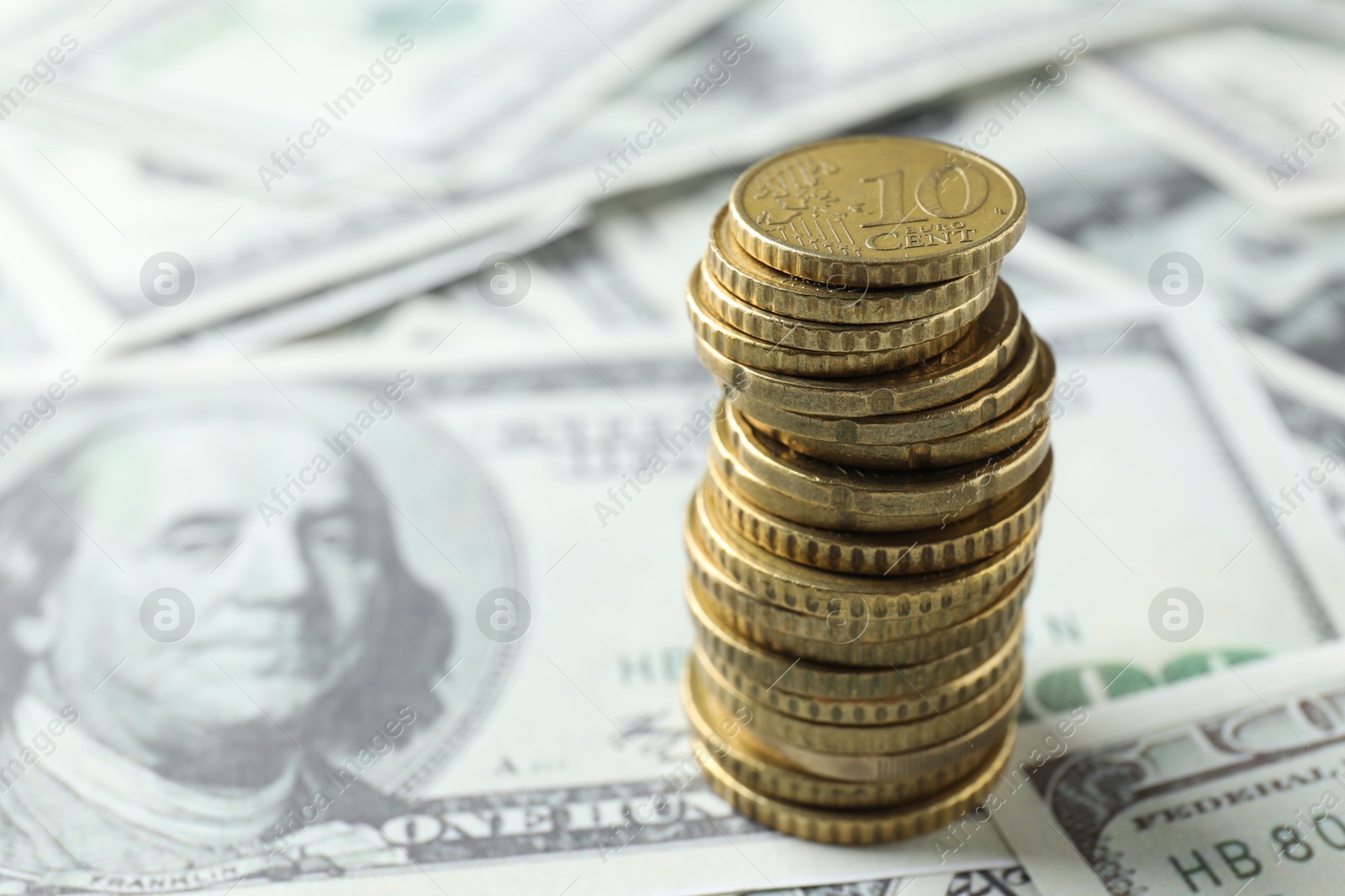 Photo of Stacked euro coins on dollar banknotes, closeup