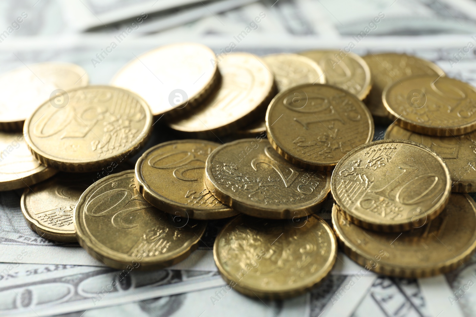 Photo of Many euro coins on dollar banknotes, closeup