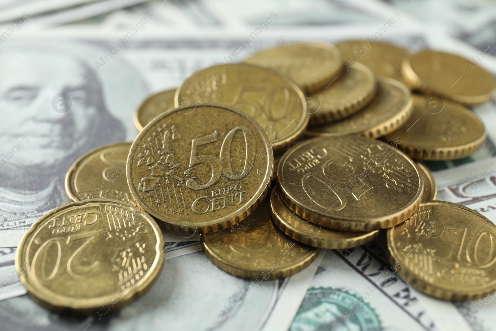 Photo of Many euro coins on dollar banknotes, closeup