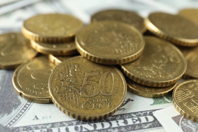 Photo of Many euro coins on dollar banknotes, closeup