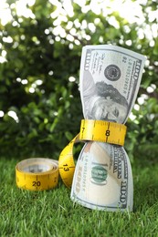 Budgeting. Dollar banknotes and measuring tape on green grass