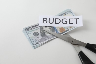 Dollar banknotes, scissors and paper with word Budget on white background