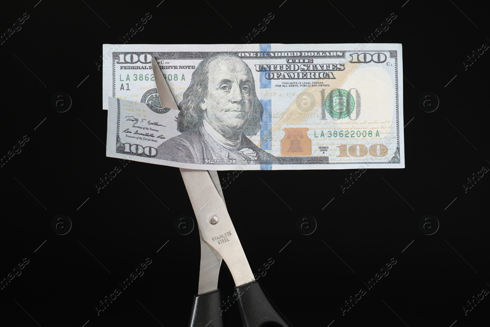 Photo of Budgeting. Cutting dollar banknote with scissors on black background, closeup