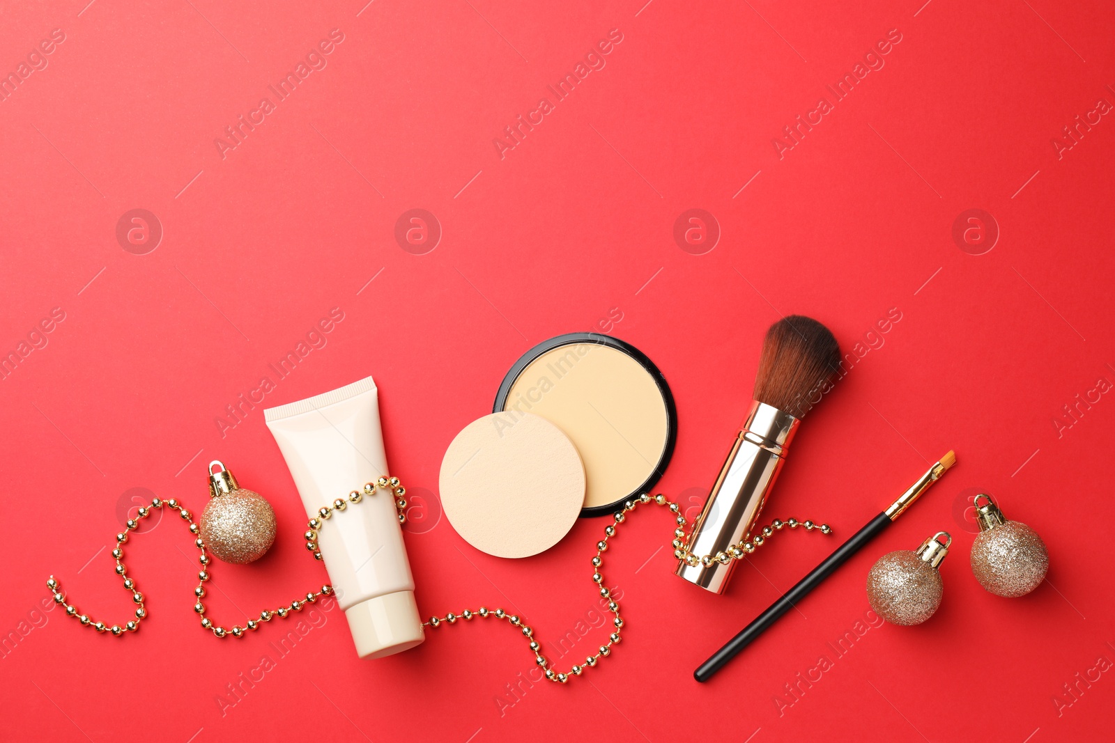 Photo of Flat lay composition with makeup products and Christmas decor on red background. Space for text