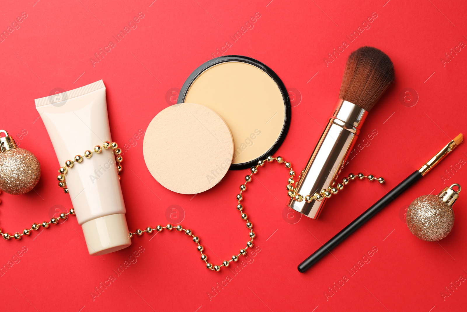 Photo of Flat lay composition with makeup products and Christmas decor on red background