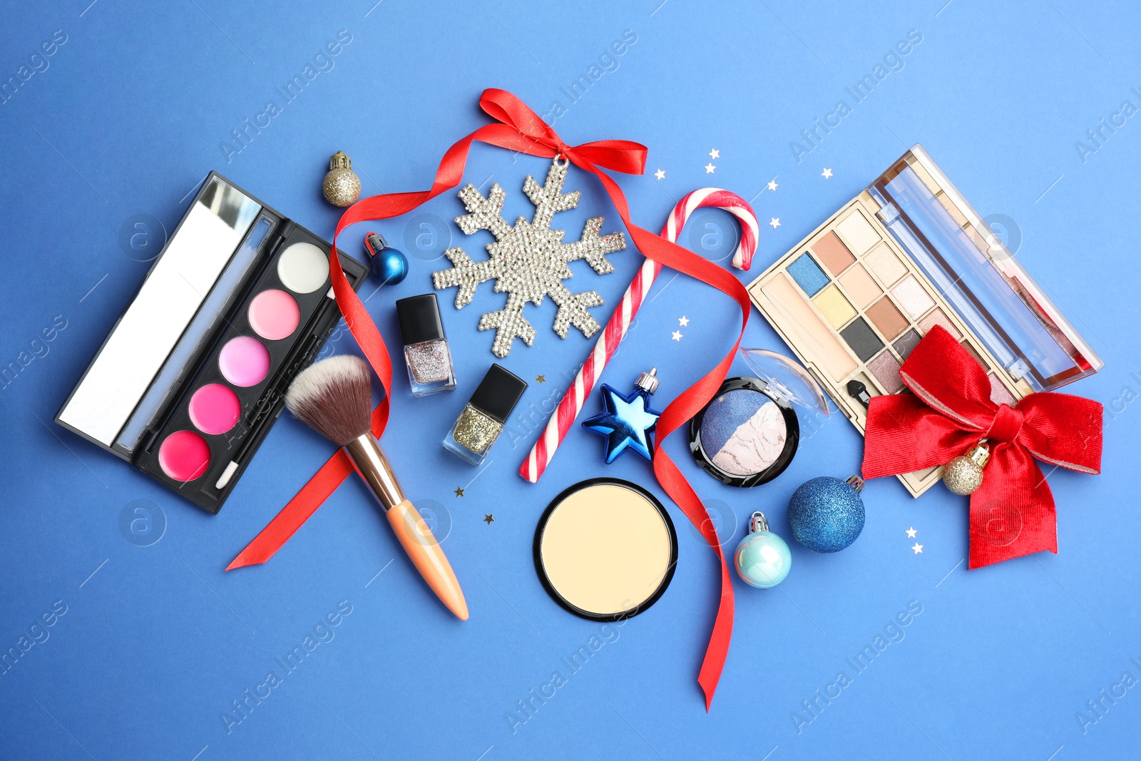 Photo of Flat lay composition with makeup products and Christmas decor on blue background