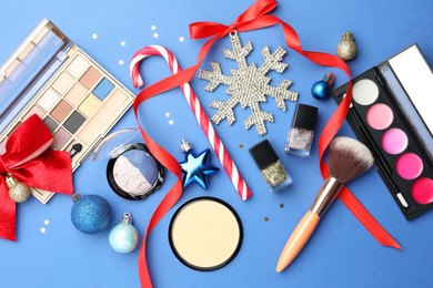 Photo of Flat lay composition with makeup products and Christmas decor on blue background