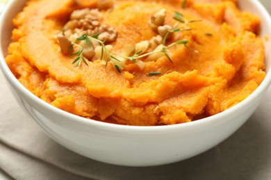 Delicious mashed sweet potatoes and nuts in bowl on table, closeup