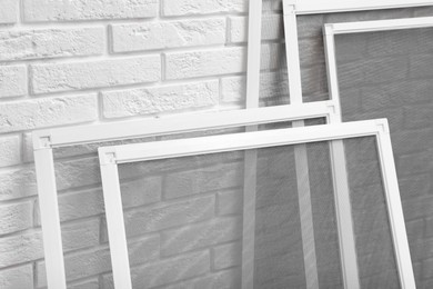 Photo of Set of window screens near white brick wall, closeup