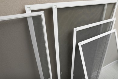 Set of window screens near beige wall indoors, closeup