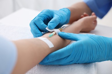 Nurse inserting IV into arm of patient in hospital, closeup