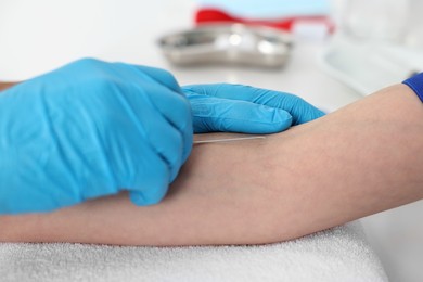 Photo of Nurse inputting catheter for IV drip in patient hand, closeup