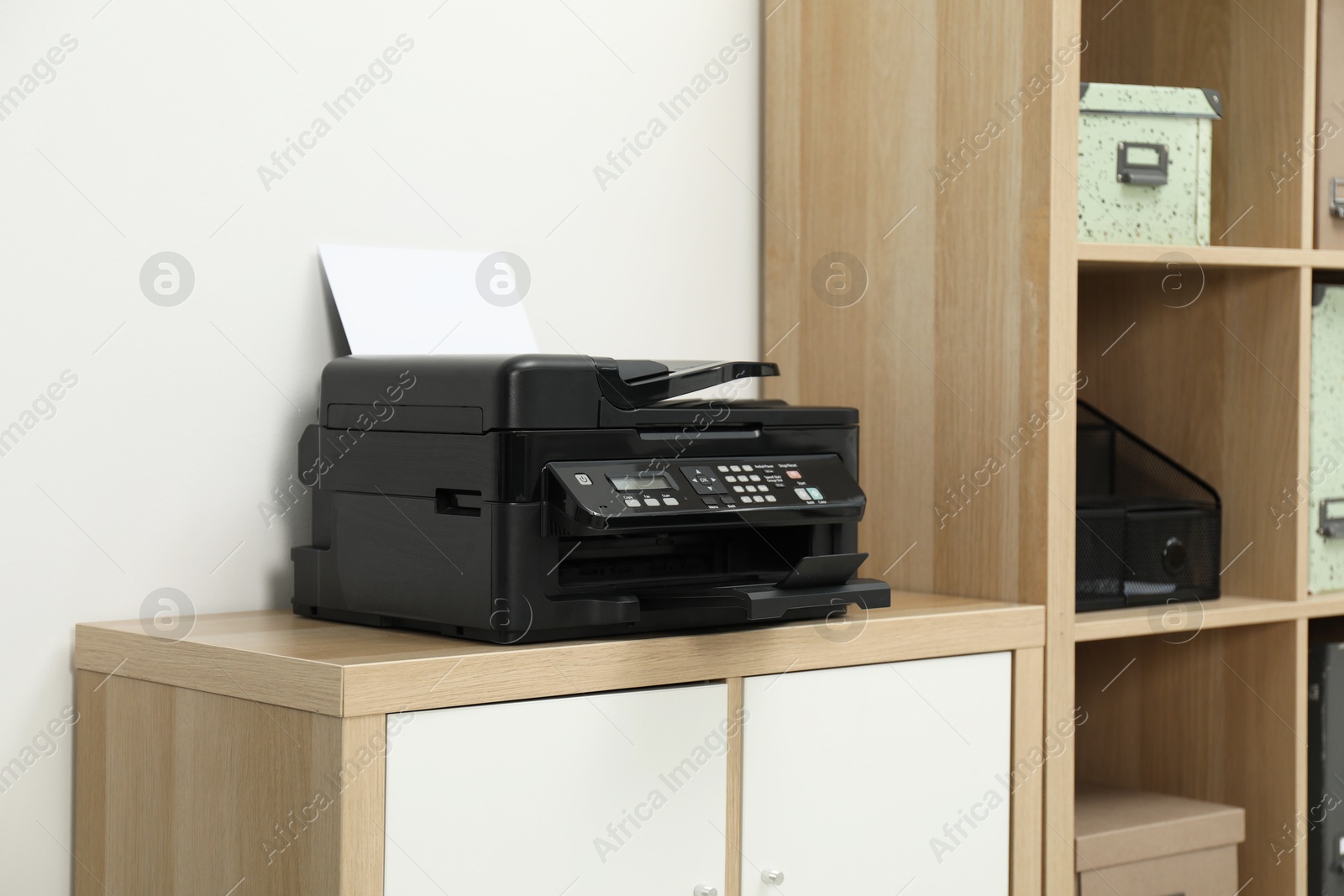 Photo of Modern printer with paper on wooden nightstand in office