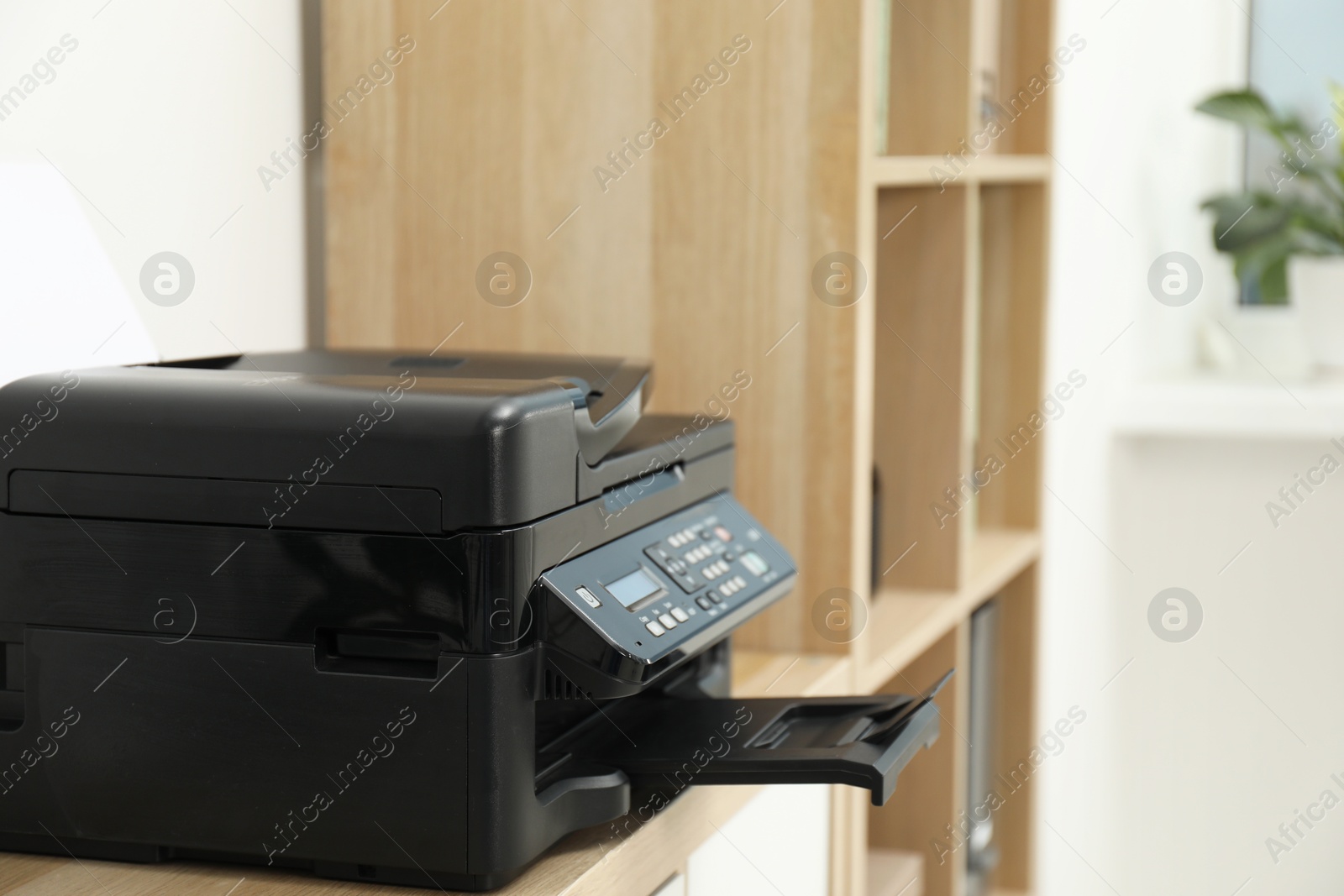 Photo of Modern printer on wooden nightstand in office