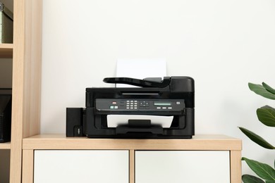 Photo of Modern printer with paper on wooden nightstand in office