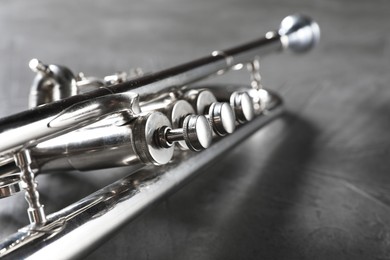 Closeup view of shiny trumpet on grey textured table. Wind musical instrument