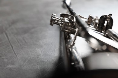 Photo of Closeup view of shiny trumpet on grey textured table, space for text. Wind musical instrument