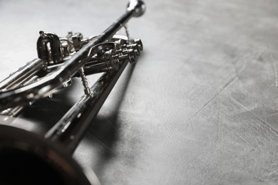 Closeup view of shiny trumpet on grey textured table, space for text. Wind musical instrument