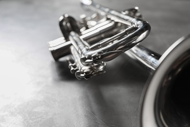 Photo of Closeup view of shiny trumpet on grey textured table. Wind musical instrument