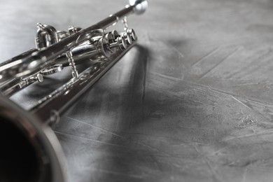 Closeup view of shiny trumpet on grey textured table, space for text. Wind musical instrument