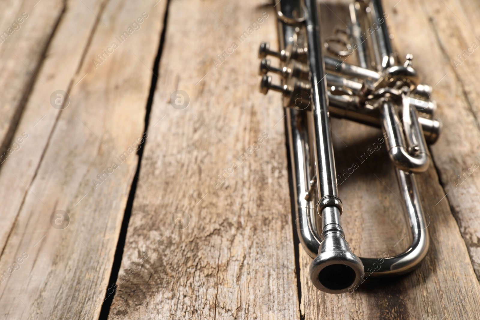 Photo of One trumpet on wooden table, closeup. Space for text