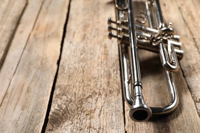 One trumpet on wooden table, closeup. Space for text