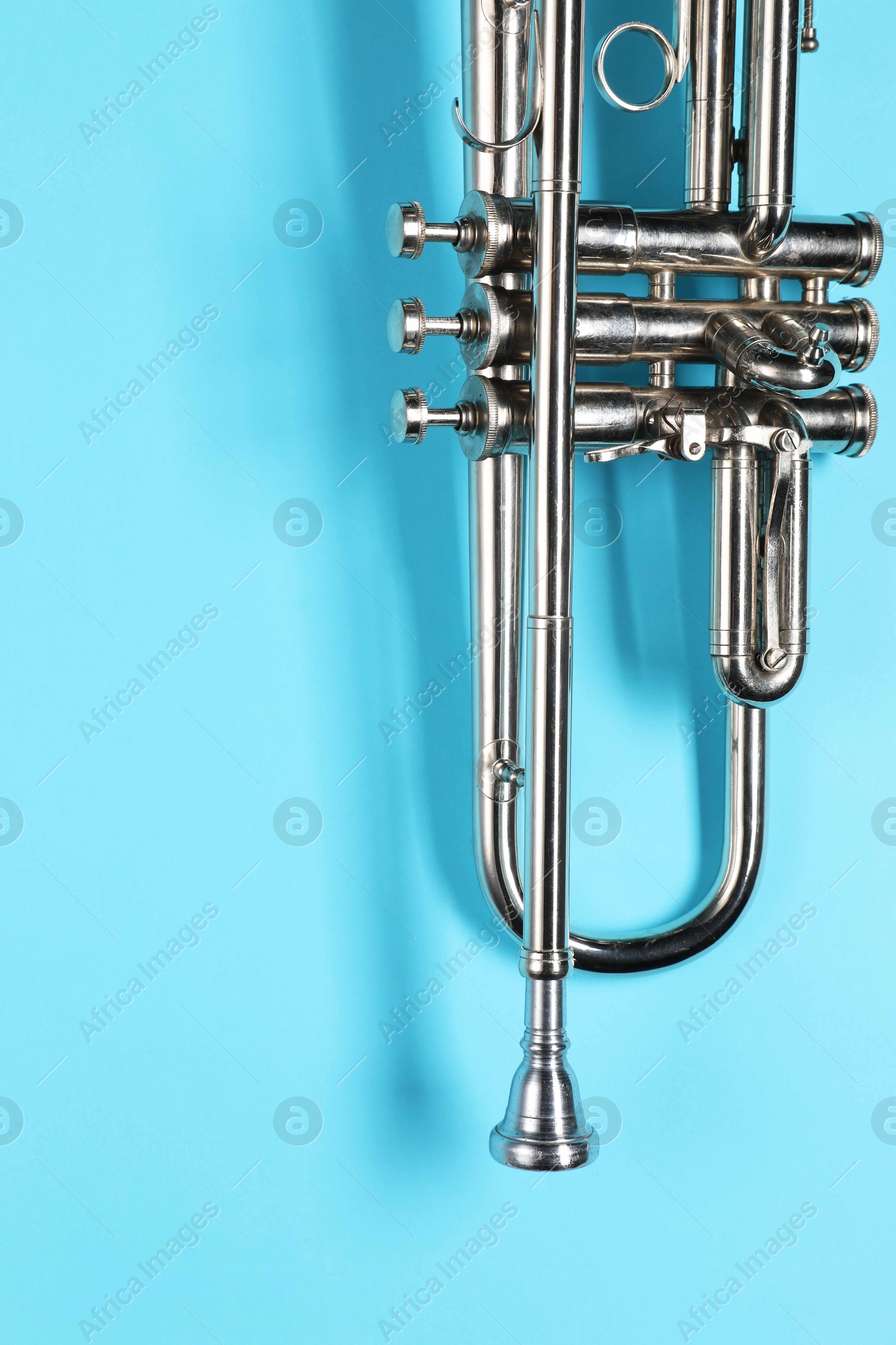 Photo of One trumpet on light blue background, top view. Space for text