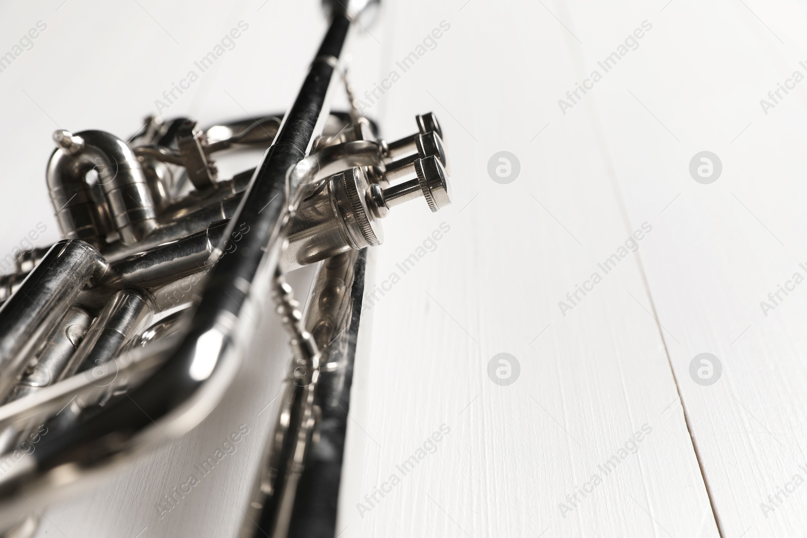 Photo of One trumpet on white wooden table, closeup. Space for text