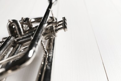 One trumpet on white wooden table, closeup. Space for text