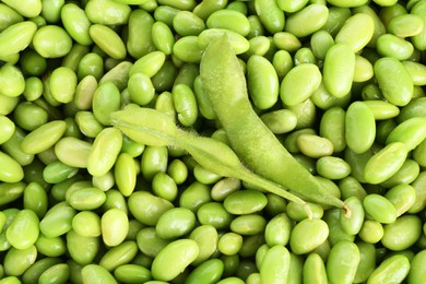 Photo of Raw green edamame pods on soybeans as background, top view