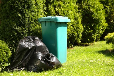 Photo of Trash bags full of garbage near bin outdoors