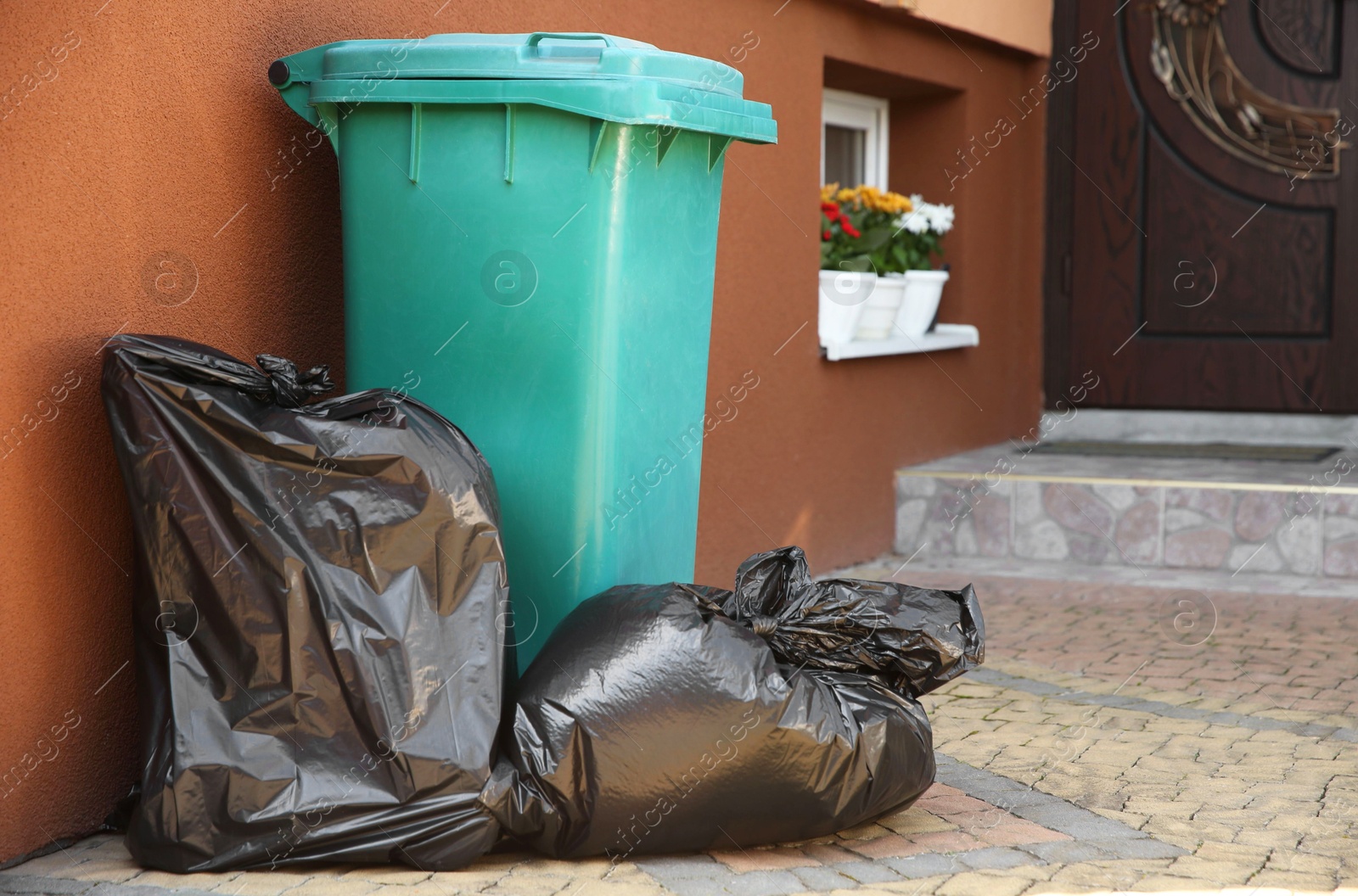 Photo of Trash bags full of garbage near bin outdoors