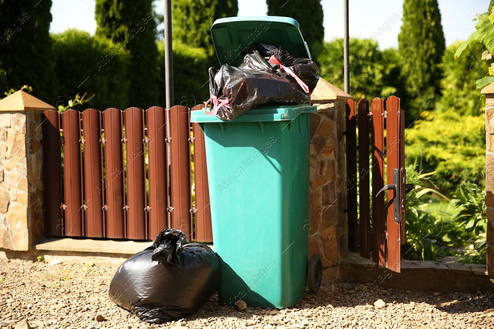 Photo of Trash bags full of garbage and bin outdoors