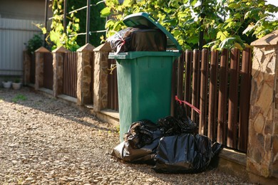 Trash bags full of garbage near bin outdoors