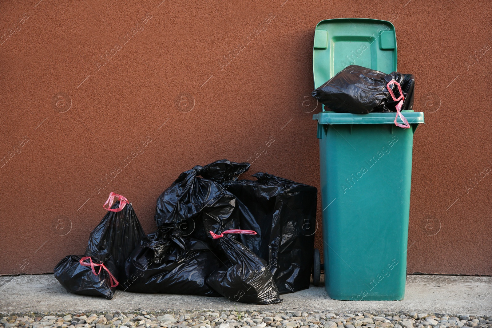 Photo of Trash bags full of garbage near bin outdoors