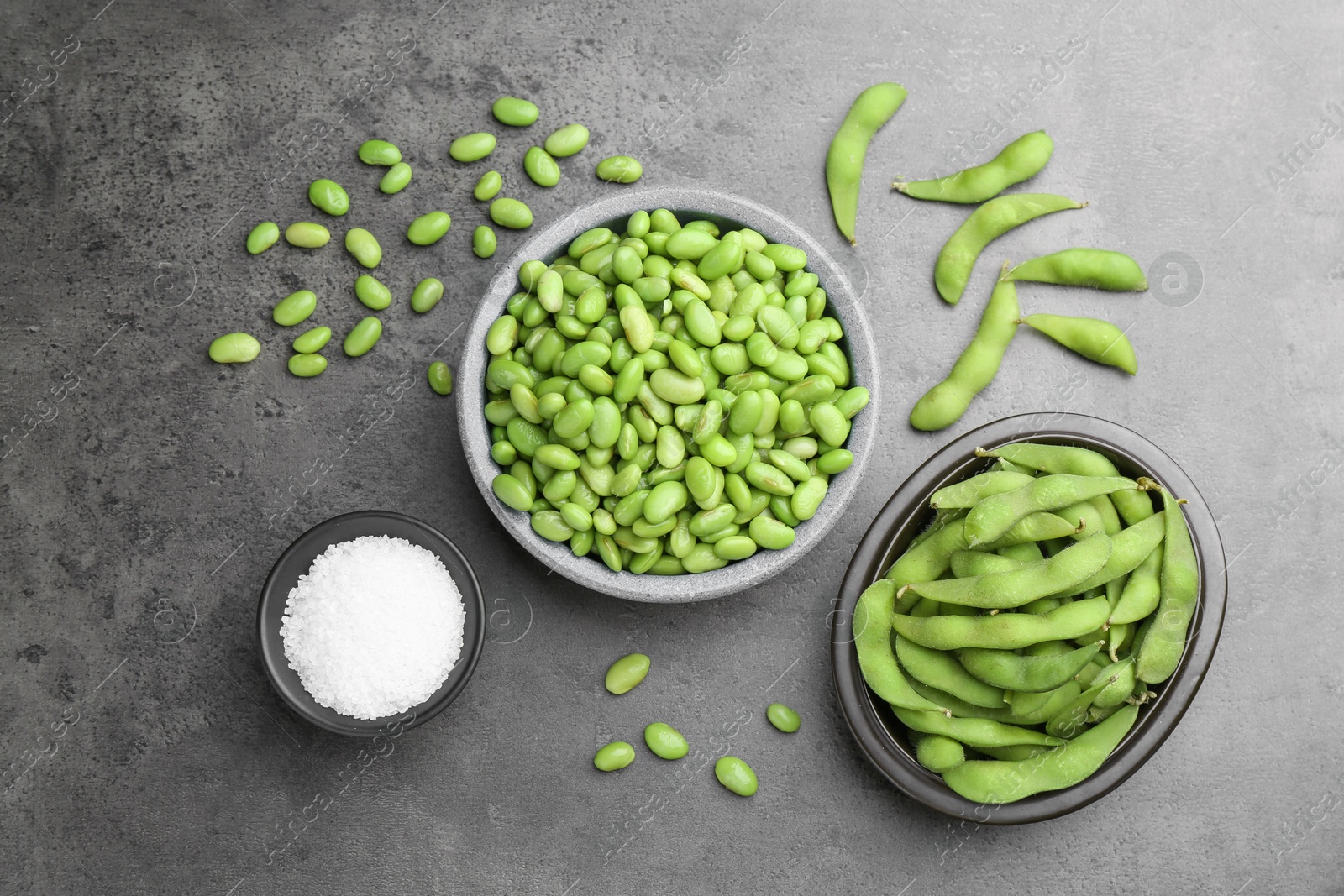 Photo of Raw green edamame soybeans and pods on grey table, flat lay