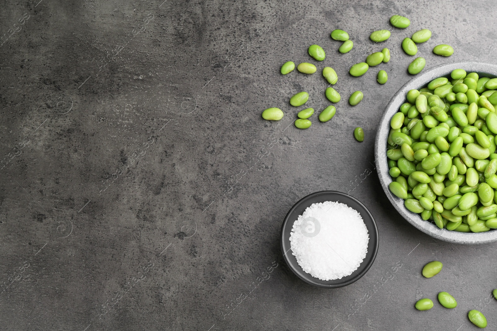 Photo of Raw green edamame soybeans and salt on grey table, top view. Space for text