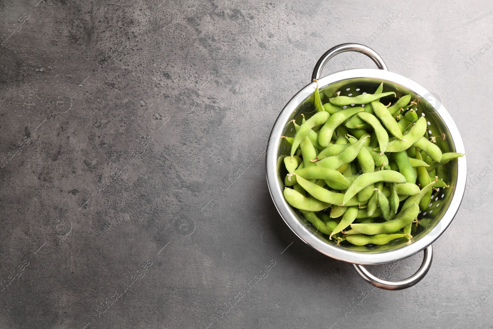 Photo of Raw green edamame soybeans and pods on grey table, top view