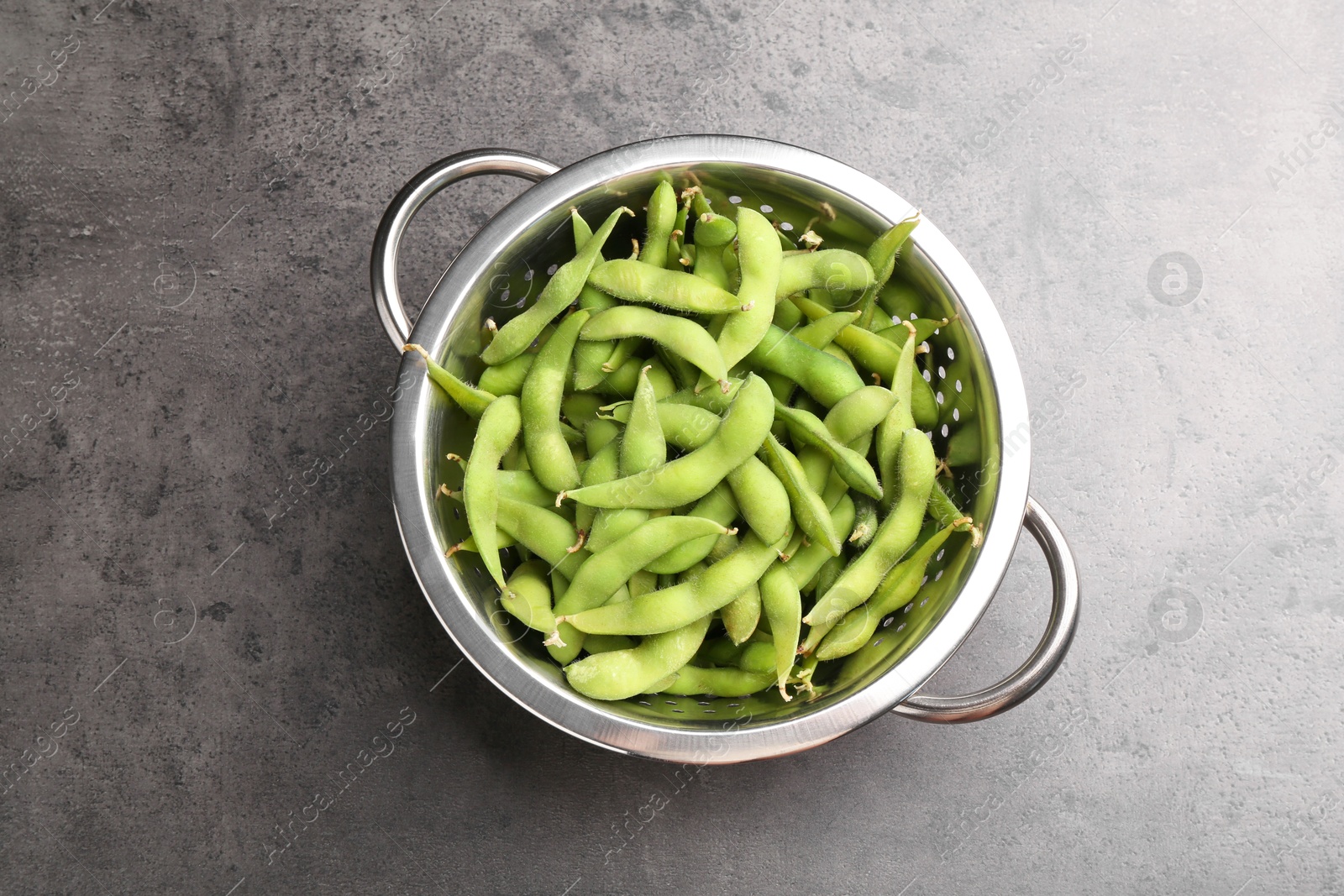 Photo of Raw green edamame soybeans and pods on grey table, top view