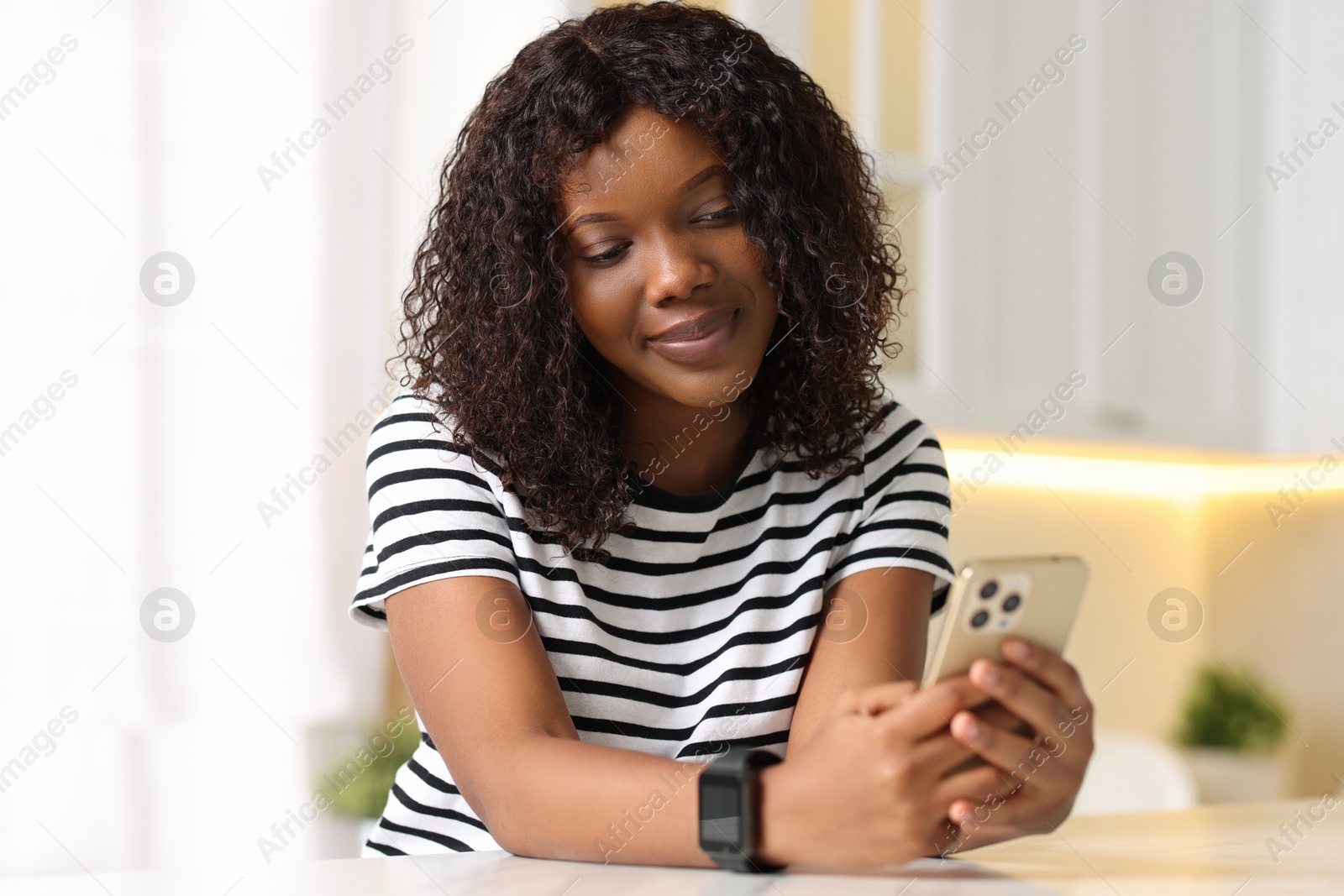 Photo of Beautiful woman using mobile phone at table indoors