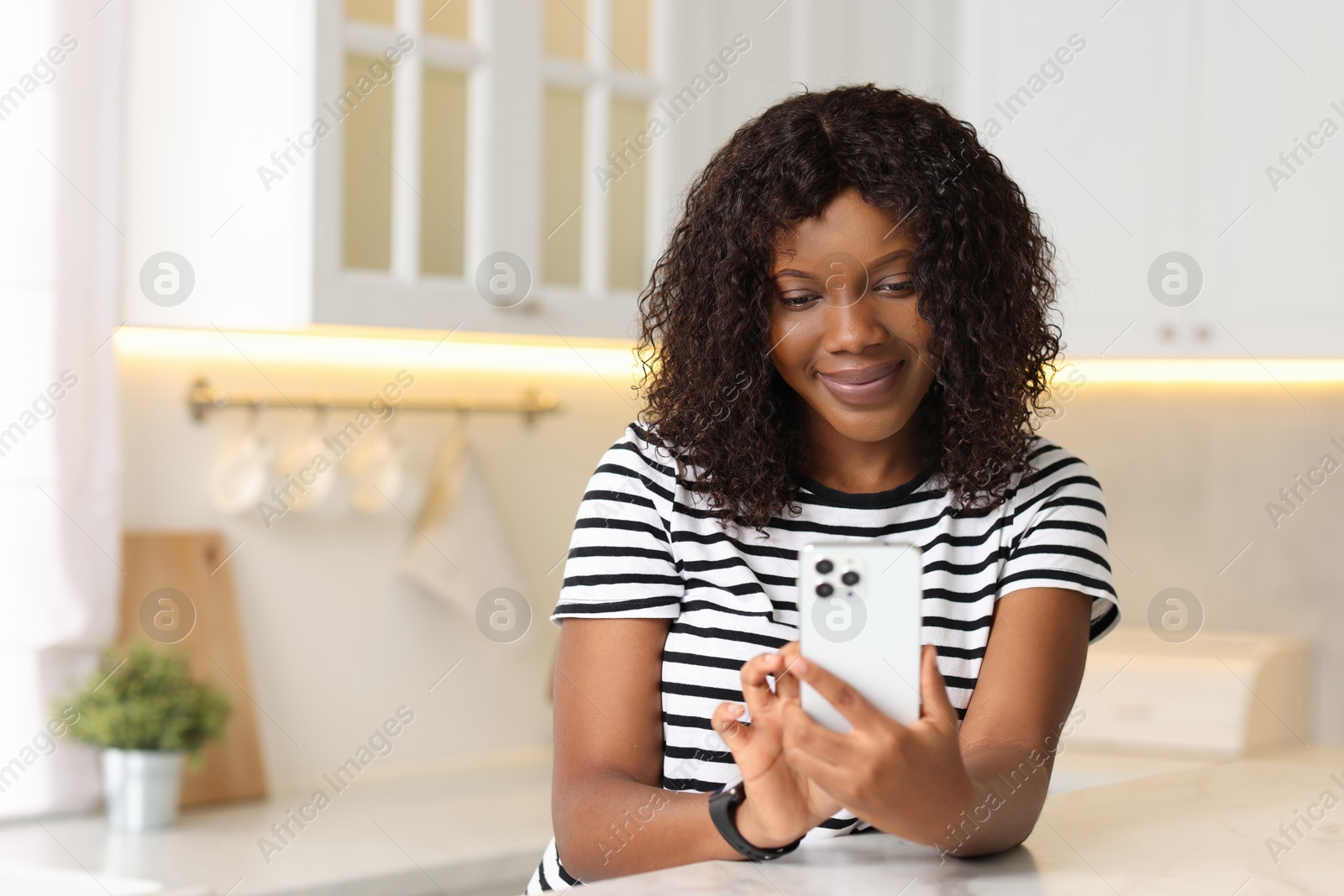 Photo of Beautiful woman using mobile phone at table indoors