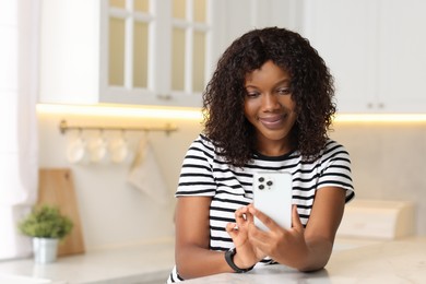 Beautiful woman using mobile phone at table indoors