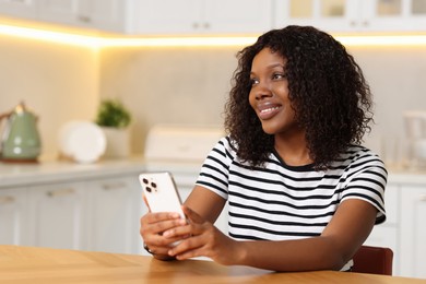 Beautiful woman with mobile phone at table indoors