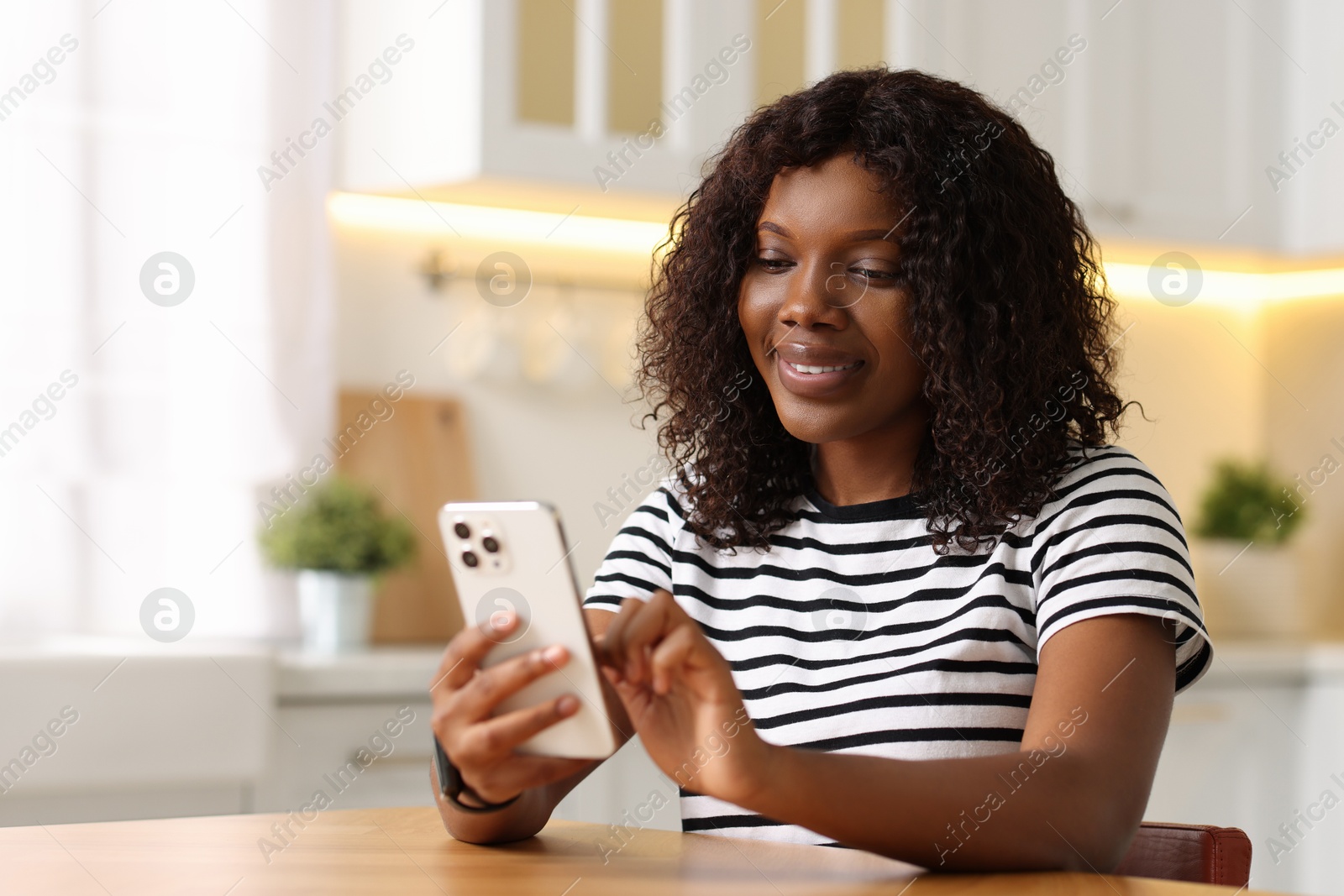 Photo of Beautiful woman using mobile phone at table indoors