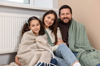 Happy family near heating radiator at home