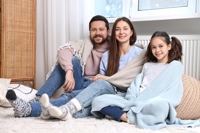 Happy family near heating radiator at home